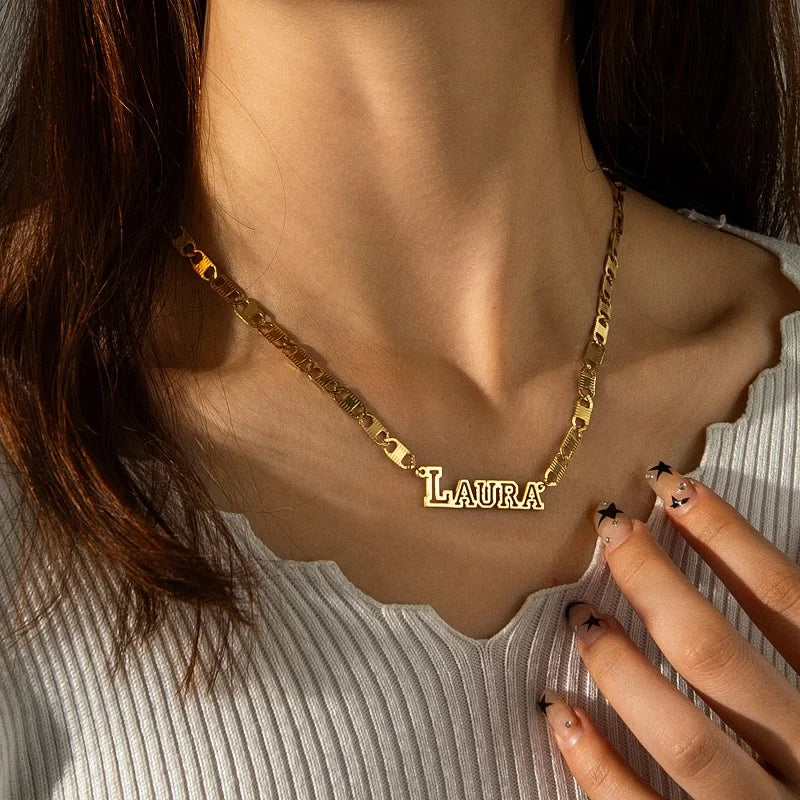 Gold necklace with 'LAURA' pendant worn by a person